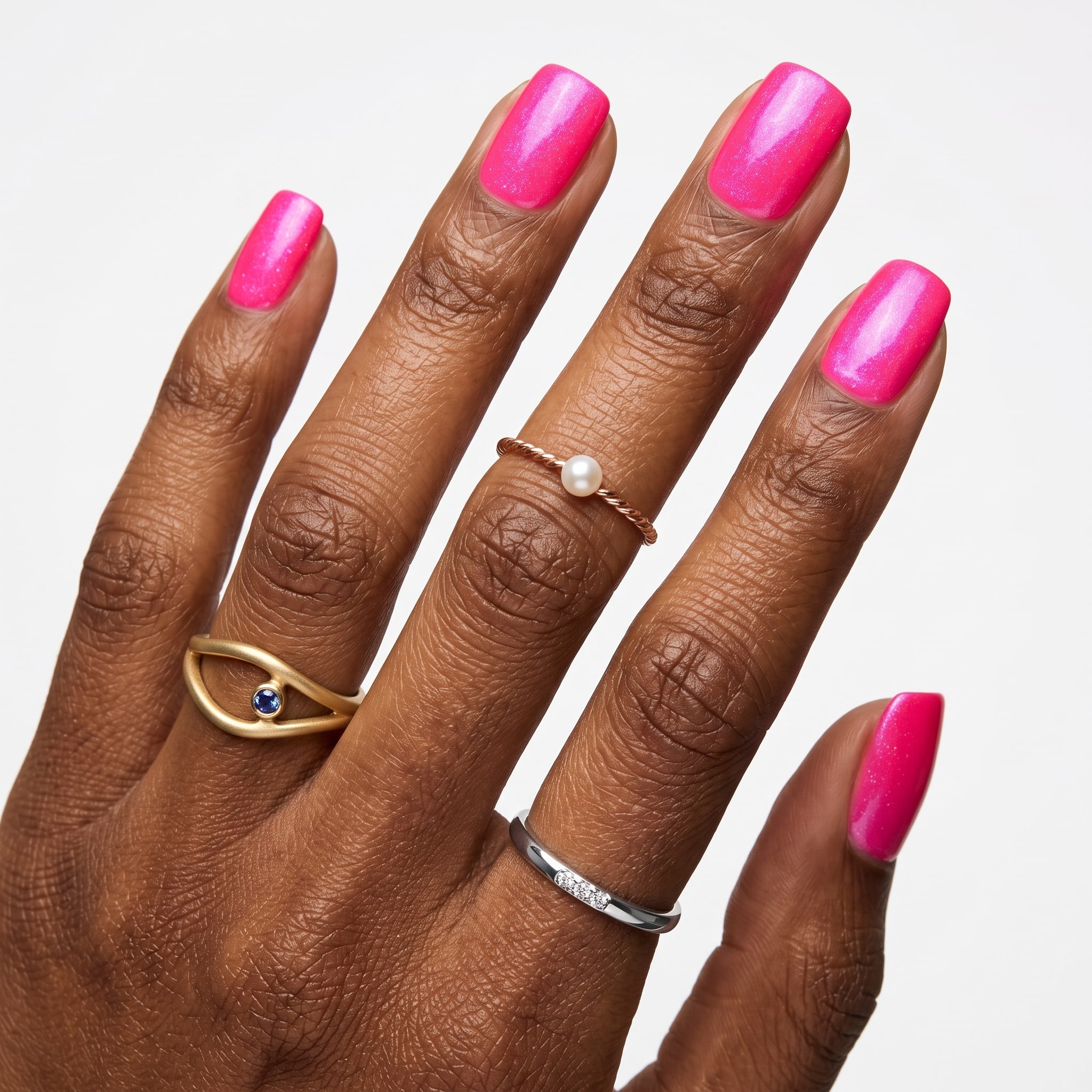 Hot pink gel nail polish on glossy almond nails with delicate gold rings