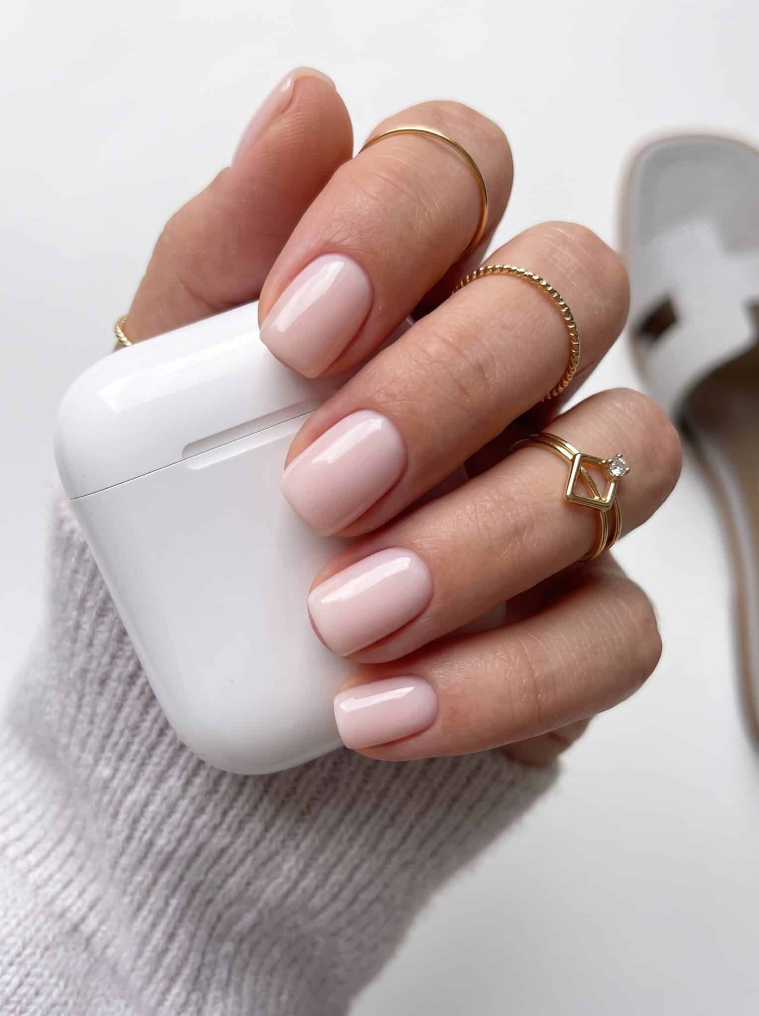 Glossy nude pink nails on almond-shaped hands with a barely-there finish