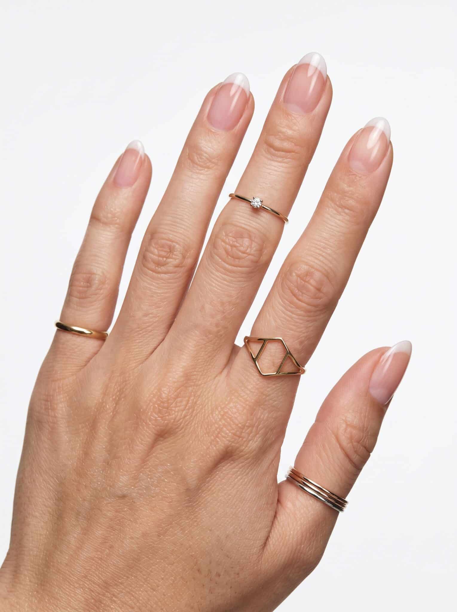 Milky soft pink manicure on short rounded nails holding a white cup
