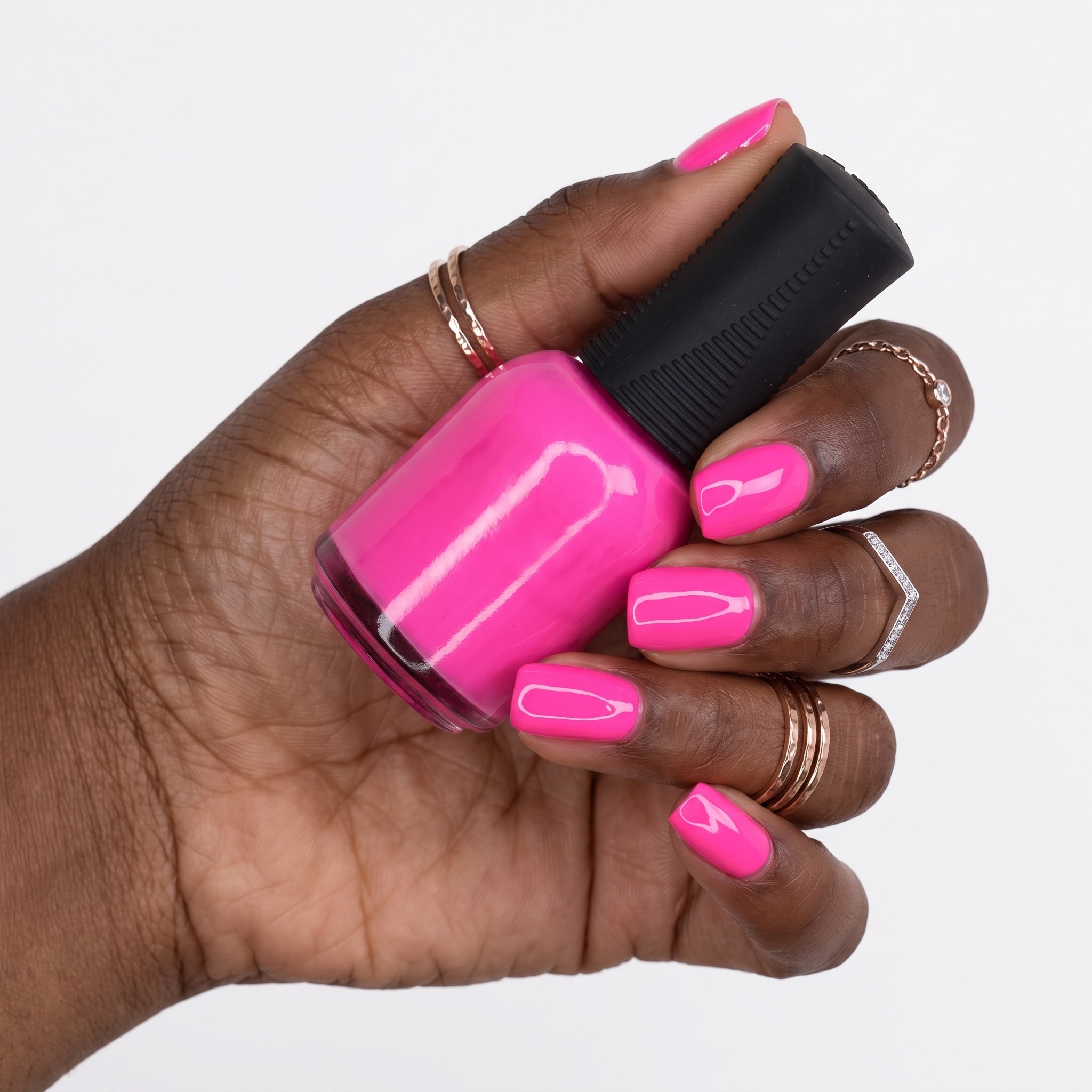 Long vivid pink nails styled with minimal gold rings