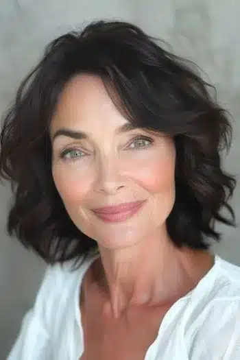 Short Hairstyles for Women Over 70 With Fine Hair - Waves with Side-Swept Bangs Hairstyle on Smiling Woman in her 60s.