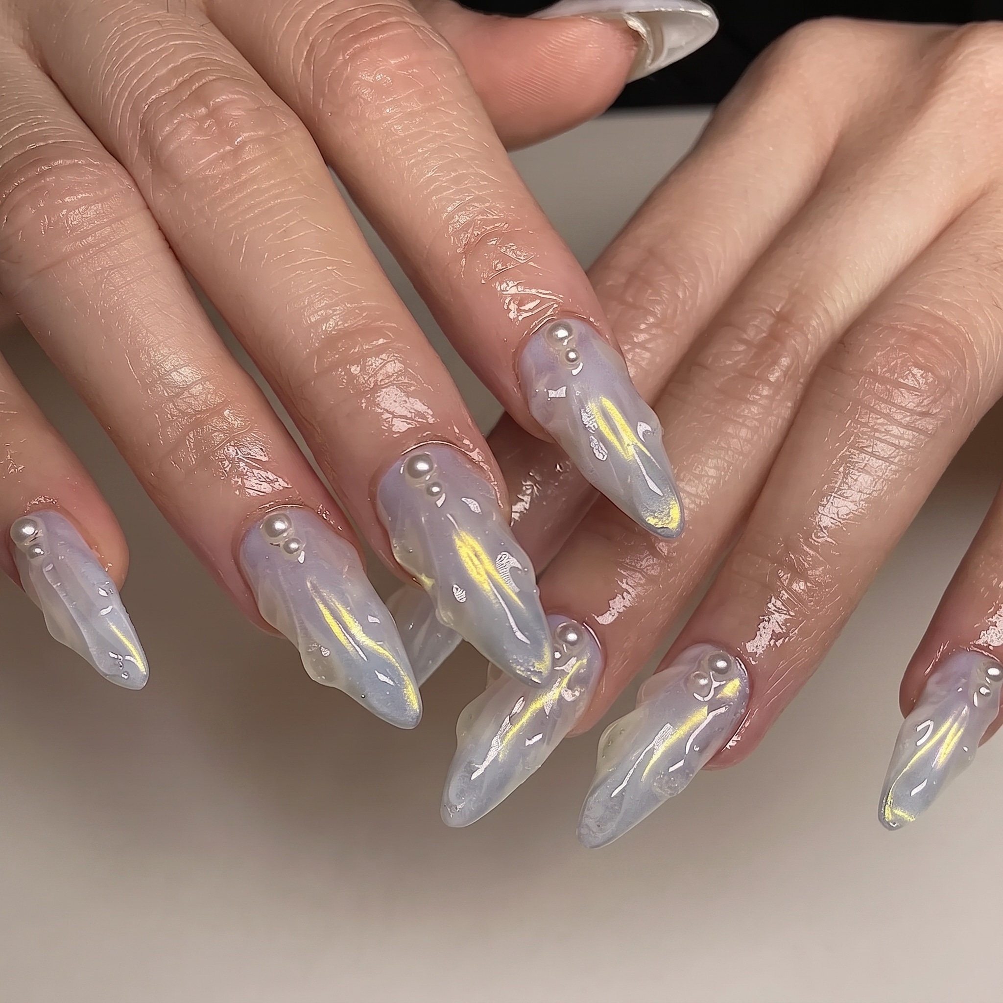 gold rate manicure with shimmering shell details and warm treasure accents