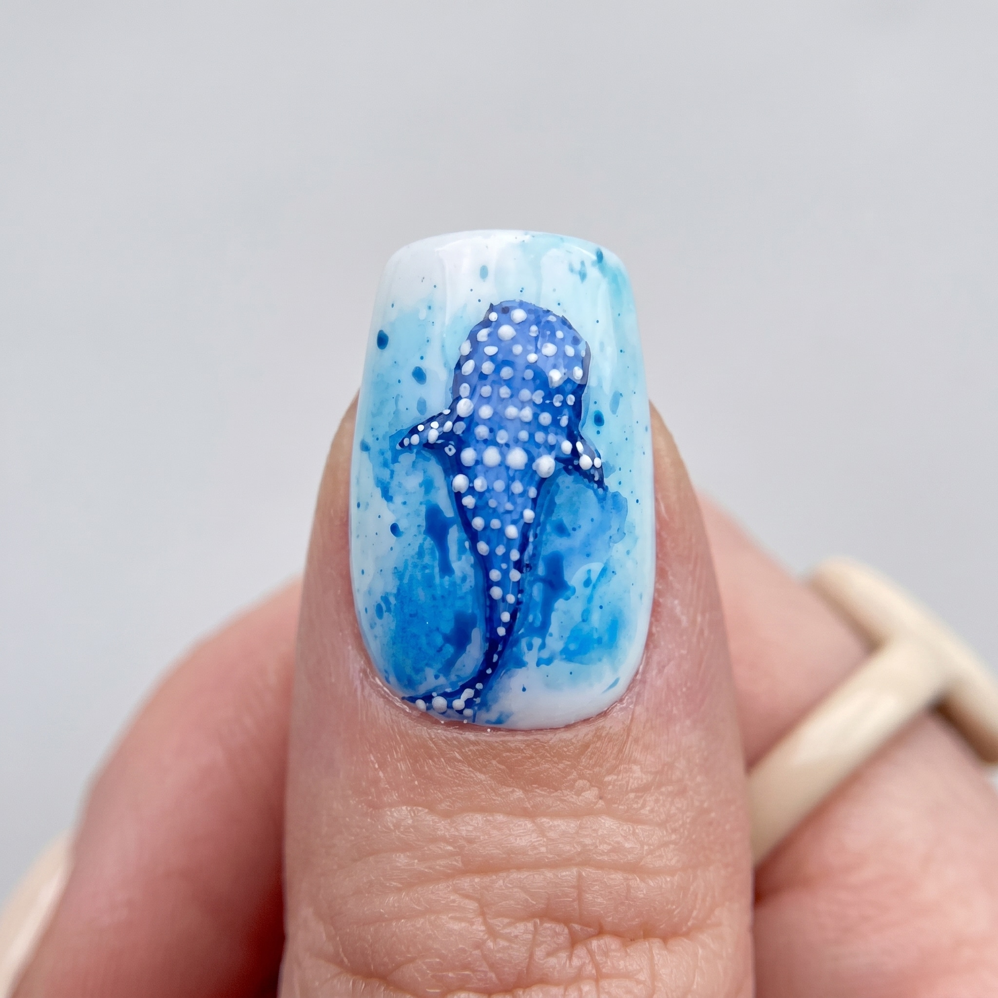 ocean blue manicure with spotted shark nail art and shimmer finish