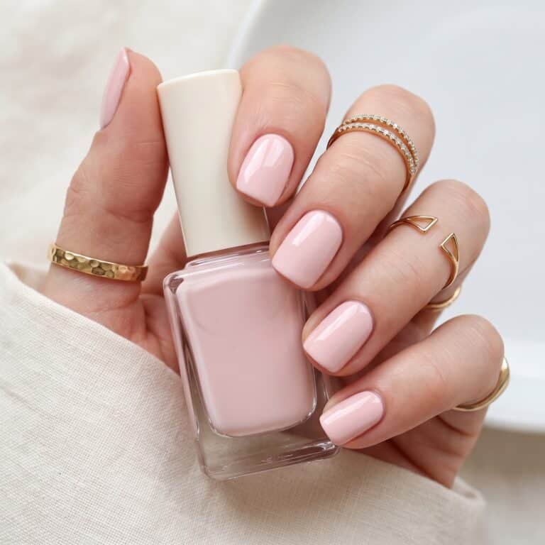 Pastel pink nail polish with soft speckled shimmer on rounded nails