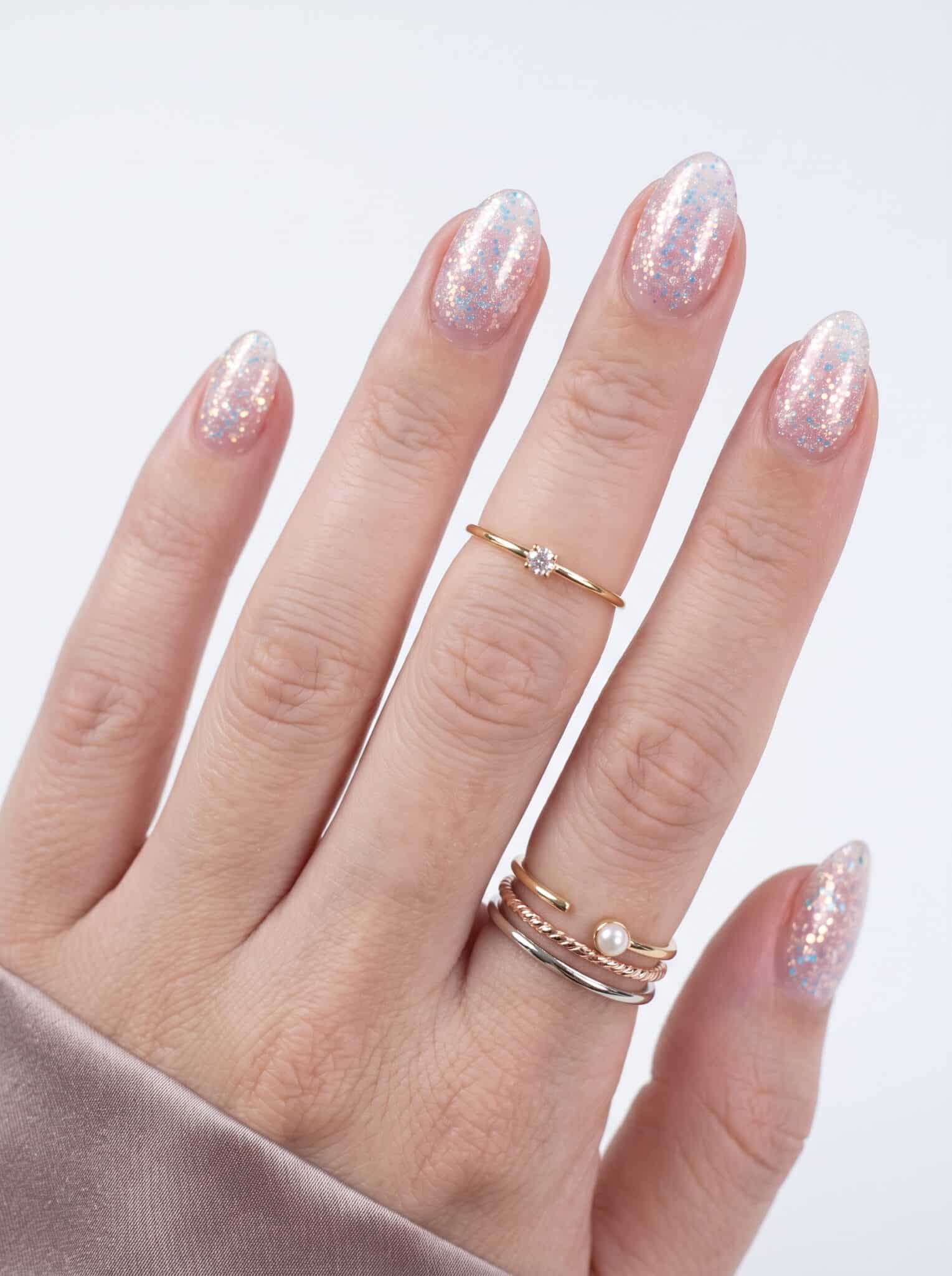 Soft pink glitter nails on hand with a delicate sparkling finish