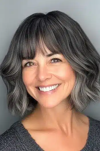 Salt and pepper wavy bob with bangs on a smiling woman