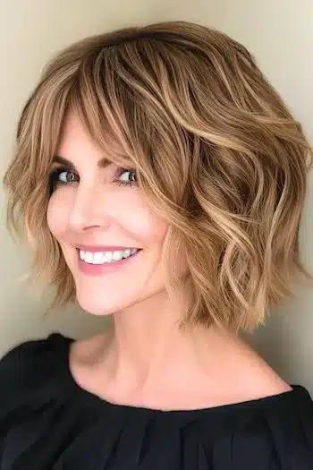 Wavy blunt bob with curtain bangs on a smiling woman