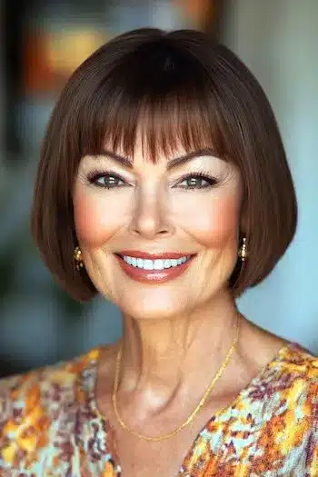 Chin-length rounded bob with piecey bangs on a smiling woman